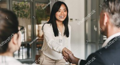 woman in job interview with man and woman, shaking hands with man