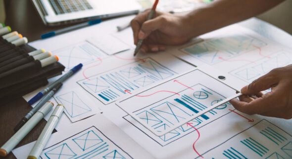 A UX graphic designer sketches out a plan for a mobile optimized website.