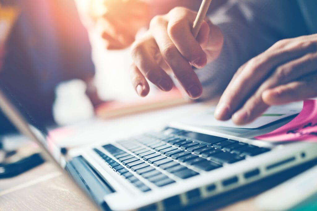 Man at desk, typing on laptop.