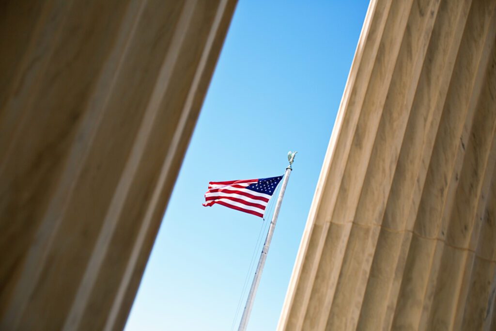 American flag viewed between building columns on Capitol Hill in Washington, DC