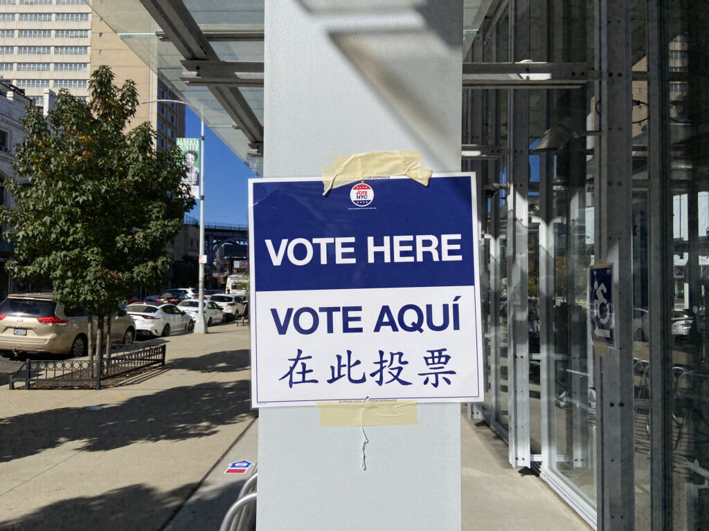 "Vote Here" sign taped to a column near a polling site.