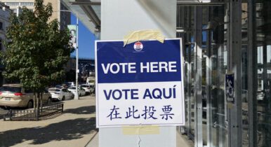 "Vote Here" sign taped to a column near a polling site.