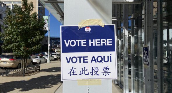 "Vote Here" sign taped to a column near a polling site.